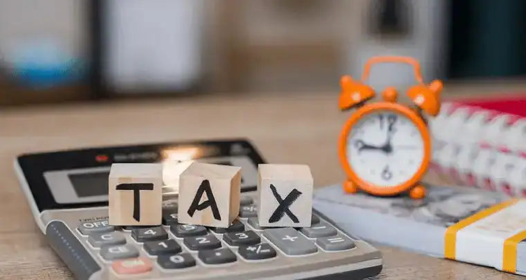 Tax calculation on digital devices using calculator and ABC blocks at office desk, representing ICT solutions for tax management and finance technology.